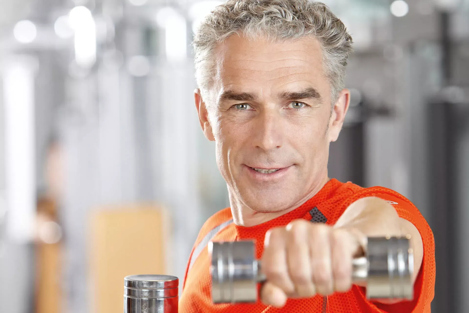Mann in mittlerem Alter trainiert mit Hanteln in einem Fitnessstudio. Mann in mittlerem Alter trainiert mit Hanteln in einem Fitnessstudio.