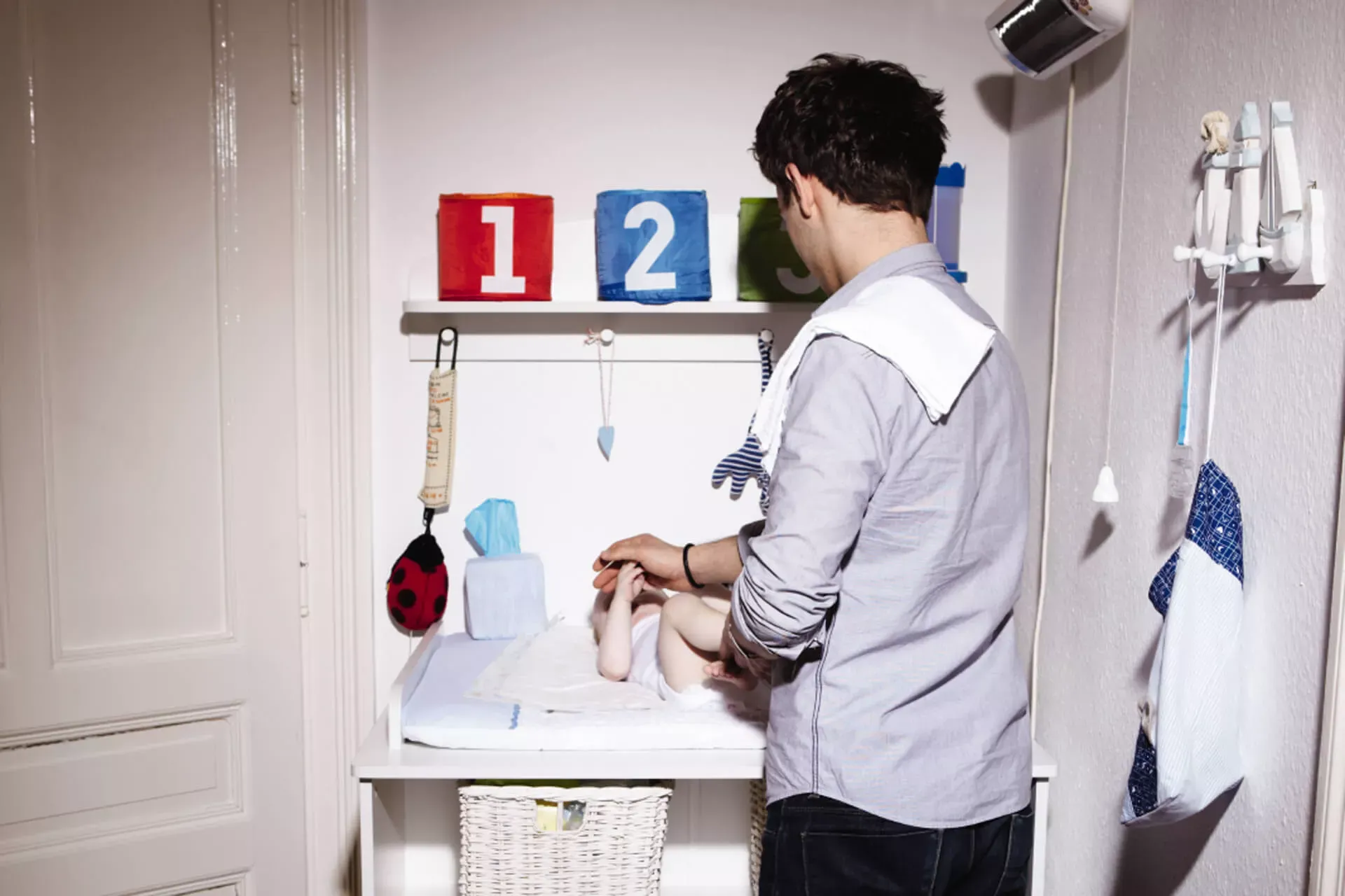 Vater steht am Wickeltisch und wechselt die Windeln bei seinem Baby. Vater steht am Wickeltisch und wechselt die Windeln bei seinem Baby.