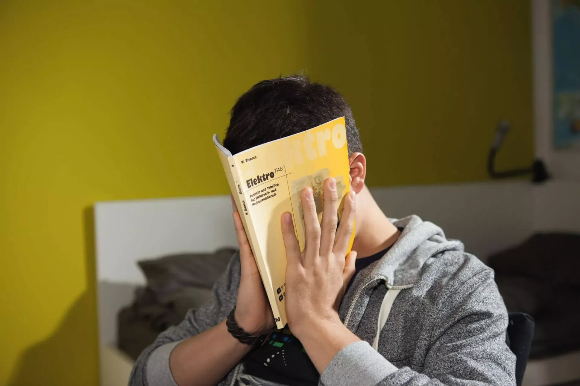Student hält sich ein Buch vors Gesicht. Student hält sich ein Buch vors Gesicht.