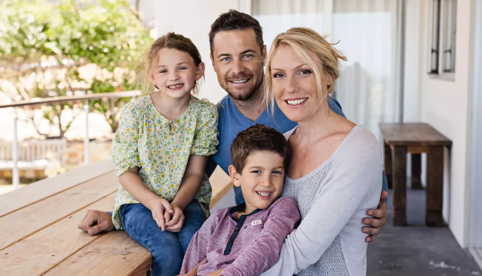 Familie mit Eltern und zwei Kindern steht zusammen auf dem Balkon. Familie mit Eltern und zwei Kindern steht zusammen auf dem Balkon.