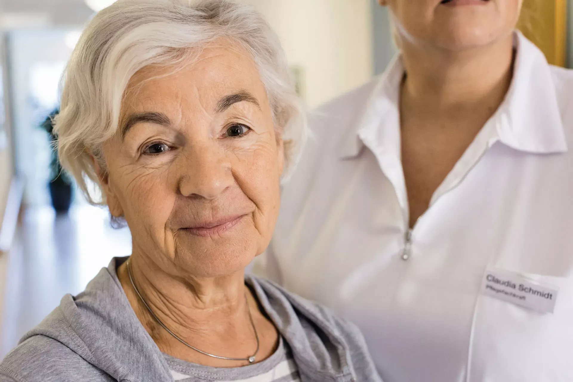 Pflegebedürftige Seniorin in Pflegeheim-Flur mit Pflegefachkraft. Pflegebedürftige Seniorin in Pflegeheim-Flur mit Pflegefachkraft.