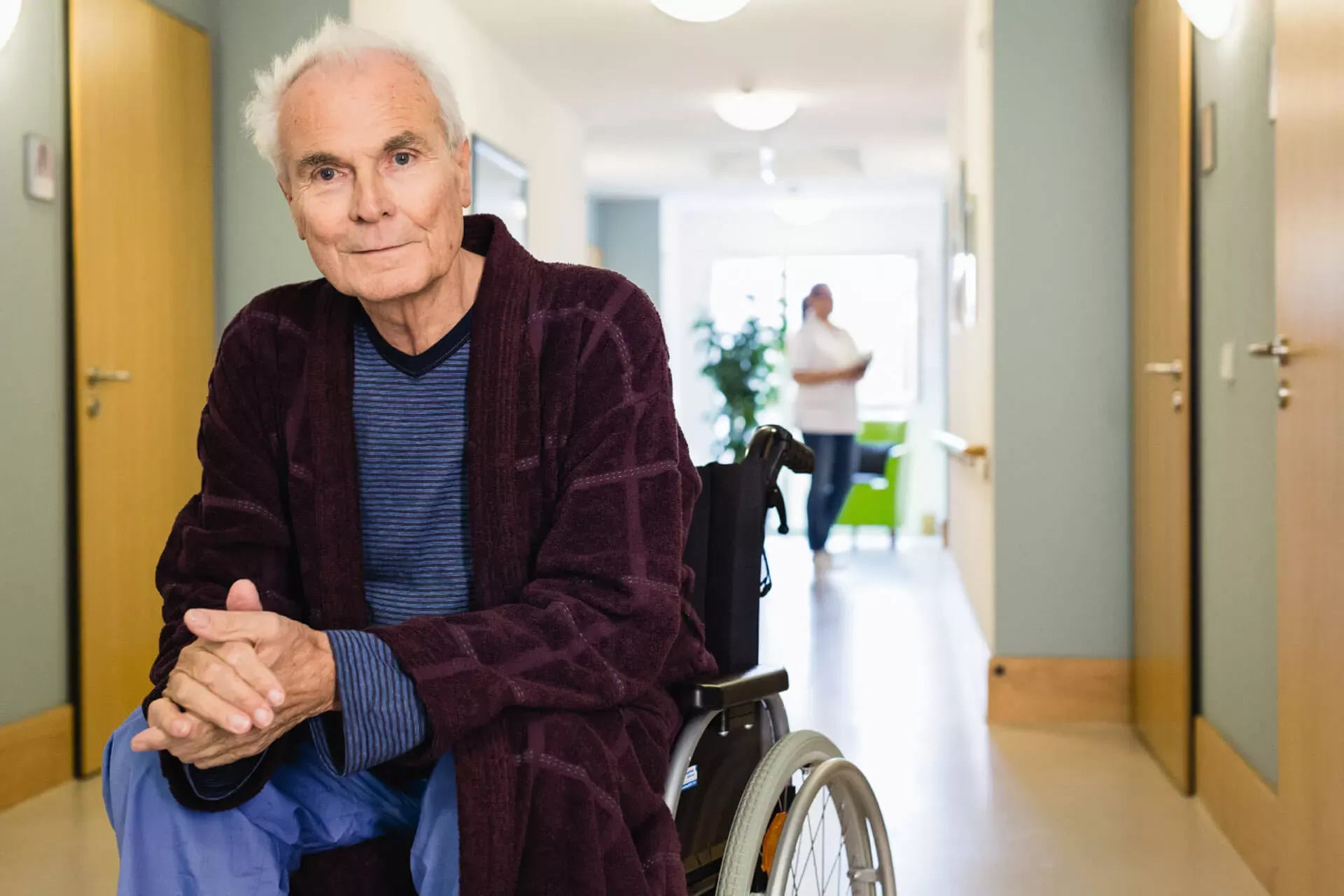 Pflegebedürftiger alter Mann sitzt im Rollstuhl auf dem Gang eines Pflegeheims. Pflegebedürftiger alter Mann sitzt im Rollstuhl auf dem Gang eines Pflegeheims.