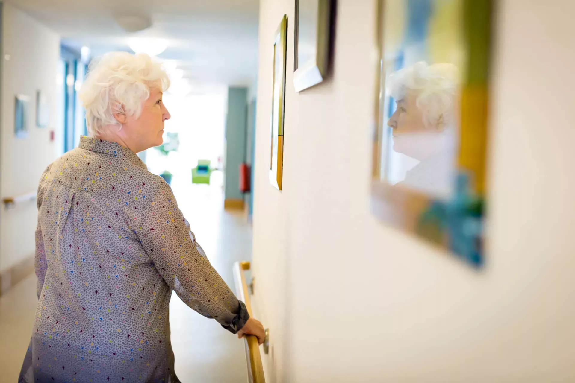 Alte Dame geht einen Flur entlang und betrachtet Bilder an der der Wand. – Bild: wdv.de © Jan Lauer Alte Dame geht einen Flur entlang und betrachtet Bilder an der der Wand. – Bild: wdv.de © Jan Lauer