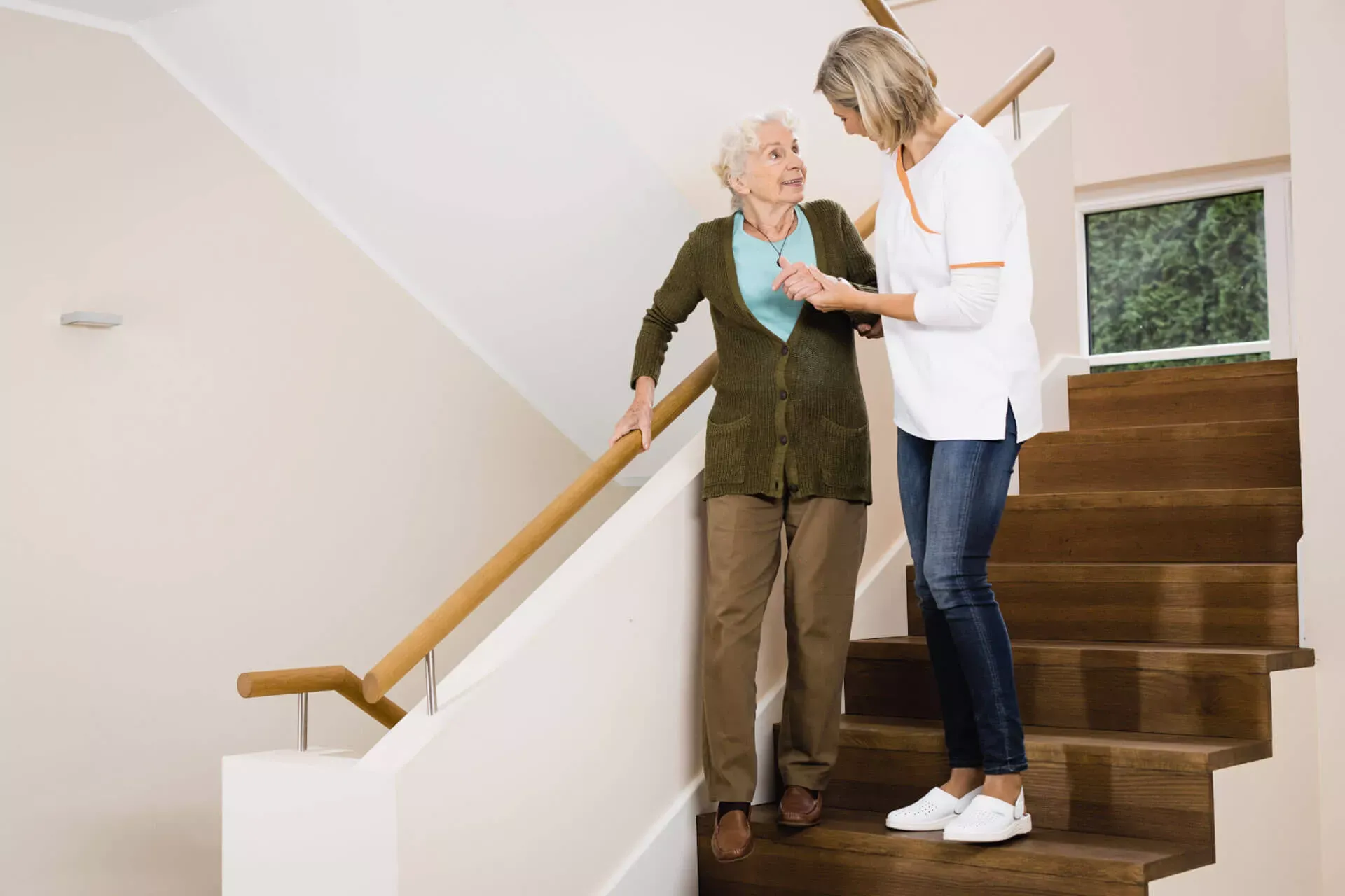 Weibliche Pflegefachkraft hilft Seniorin beim Treppensteigen. Weibliche Pflegefachkraft hilft Seniorin beim Treppensteigen.