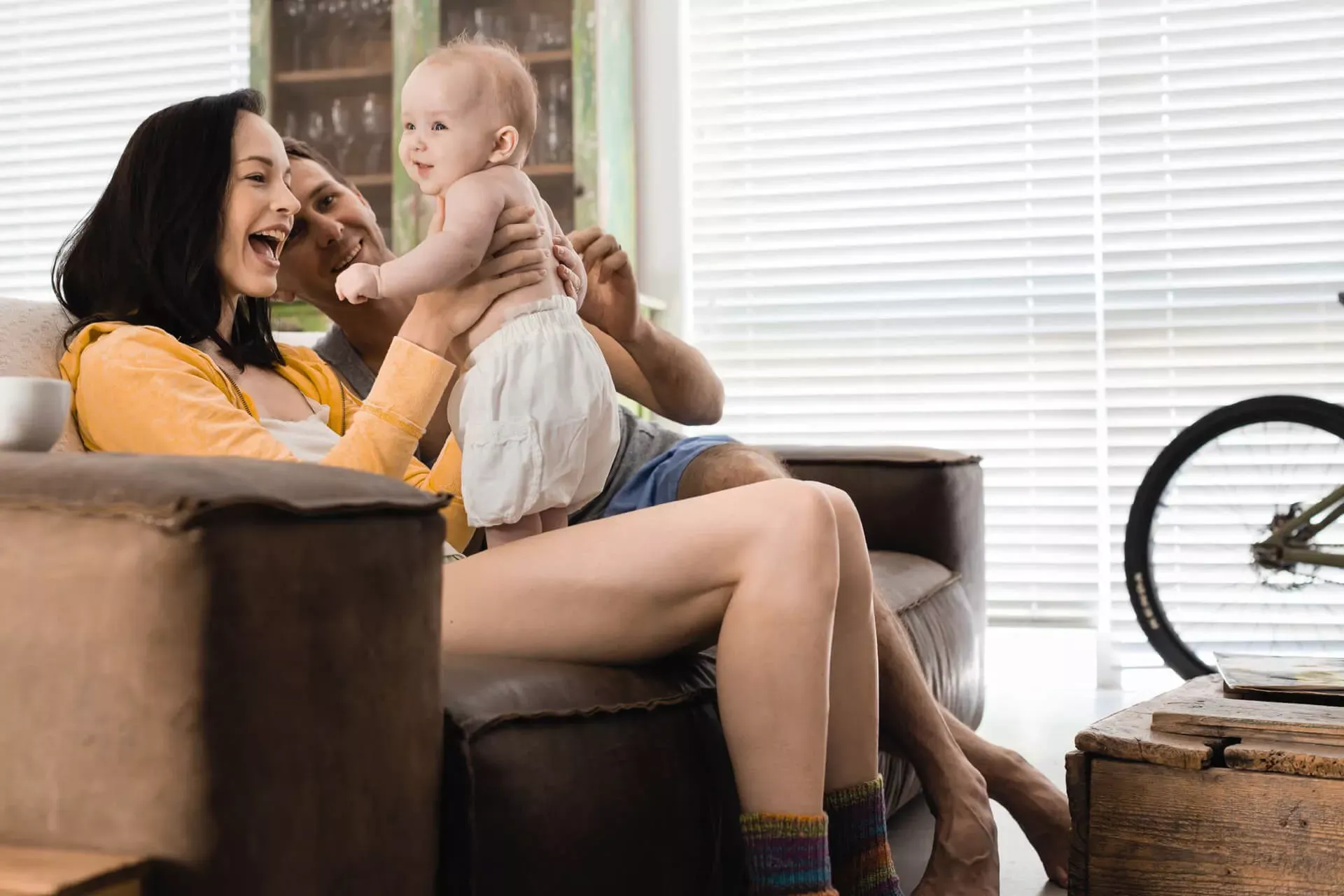 Junges Elternpaar sitzt mit Baby auf dem Sofa. Junges Elternpaar sitzt mit Baby auf dem Sofa.
