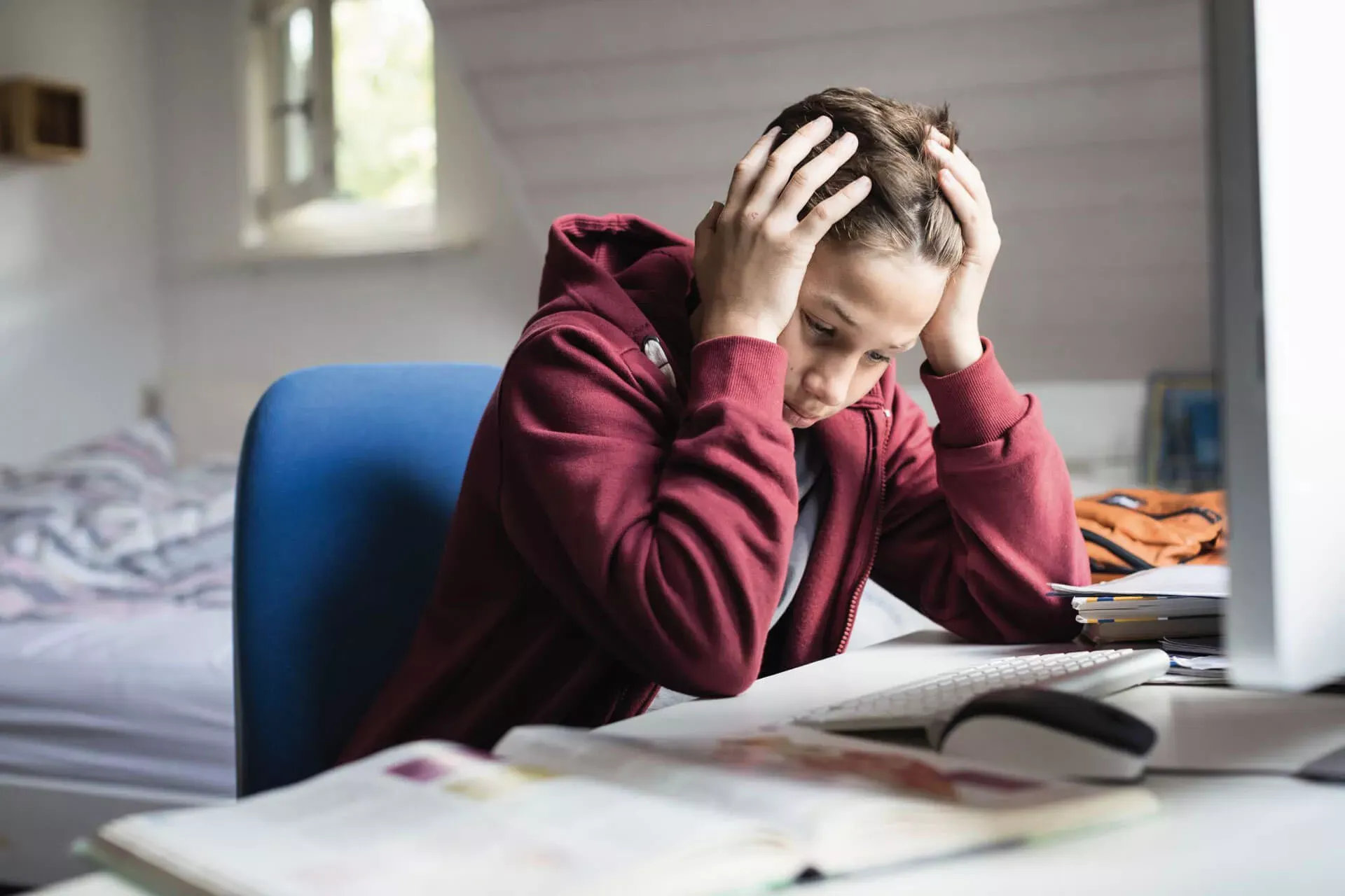 Schüler sitzt gestresst am Schreibtisch in seinem Zimmer beim Lernen. Schüler sitzt gestresst am Schreibtisch in seinem Zimmer beim Lernen.