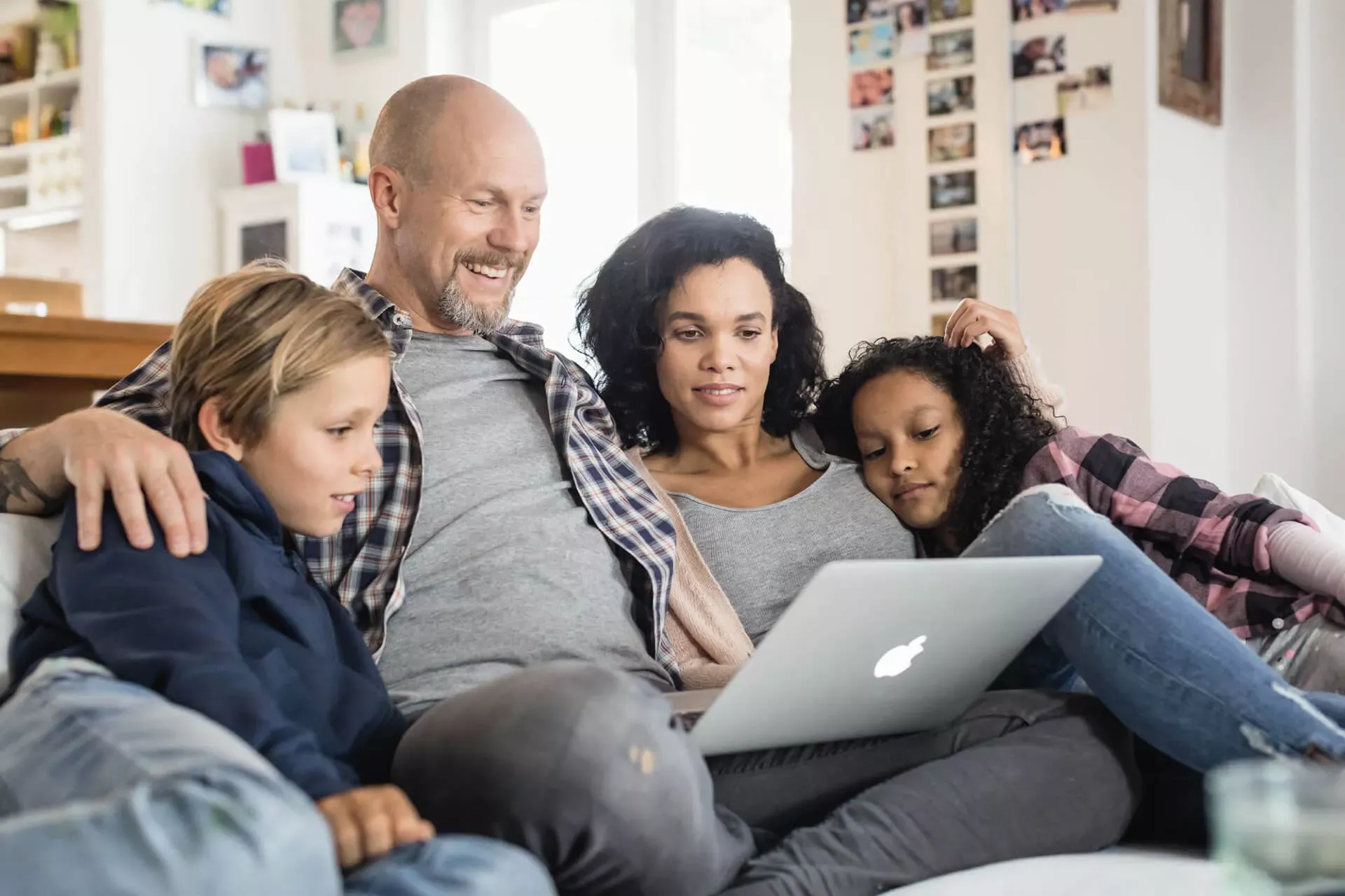 Familie mit zwei Kindern sitzt auf dem Sofa und schaut auf ein Notebook. Familie mit zwei Kindern sitzt auf dem Sofa und schaut auf ein Notebook.