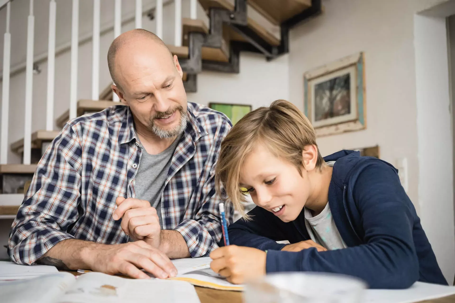 Vater sitzt mit seinem Sohn zuhause an den Schularbeiten. Vater sitzt mit seinem Sohn zuhause an den Schularbeiten.