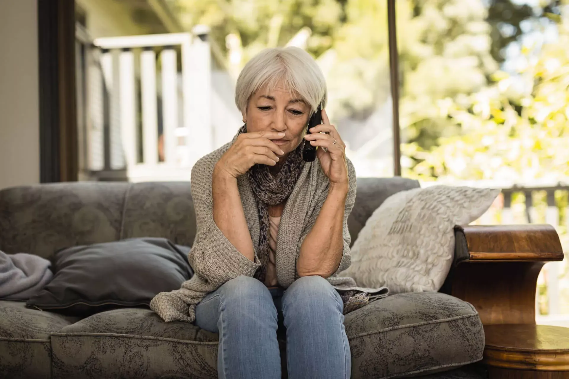 Seniorin sitzt auf ihrem Sofa im Wohnzimmer und telefoniert. Seniorin sitzt auf ihrem Sofa im Wohnzimmer und telefoniert.
