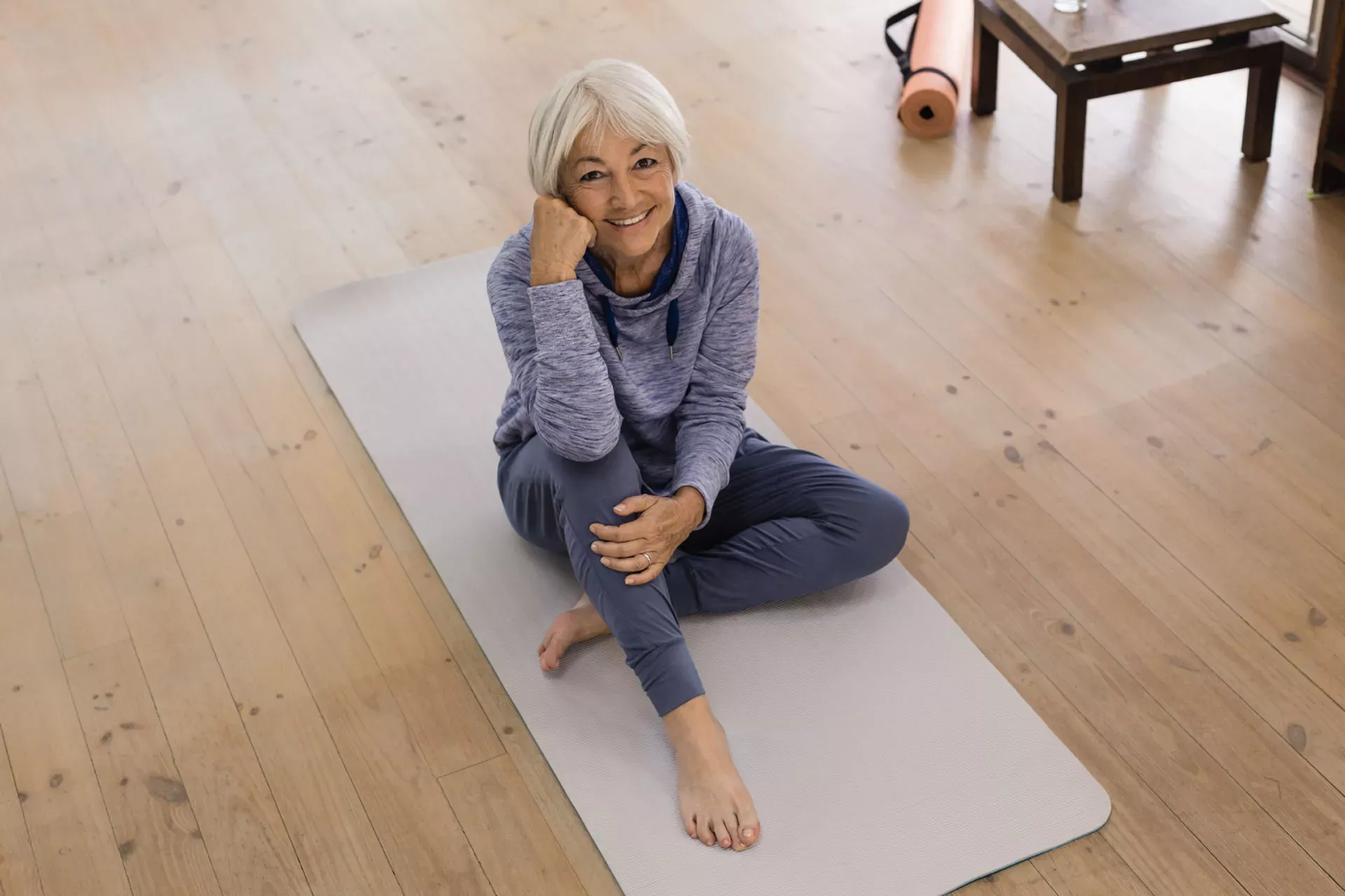 Sport im Alter ist gesund: Seniorin sitzt in Sportkleidung lächelnd auf einer Yogamatte. Sport im Alter ist gesund: Seniorin sitzt in Sportkleidung lächelnd auf einer Yogamatte.