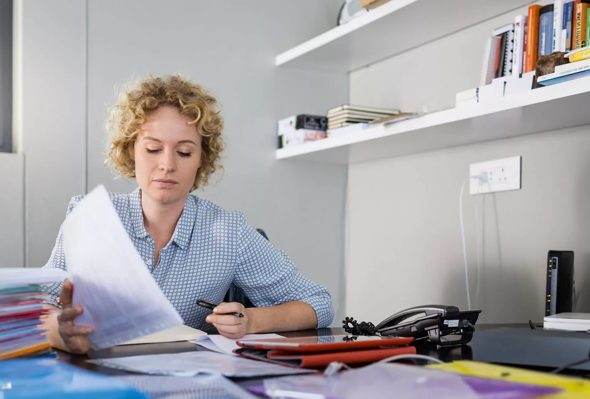 Junge Frau sitzt am Schreibtisch und sichtet Unterlagen. – Bildnachweis: wdv.de © Jan Lauer Junge Frau sitzt am Schreibtisch und sichtet Unterlagen. – Bildnachweis: wdv.de © Jan Lauer