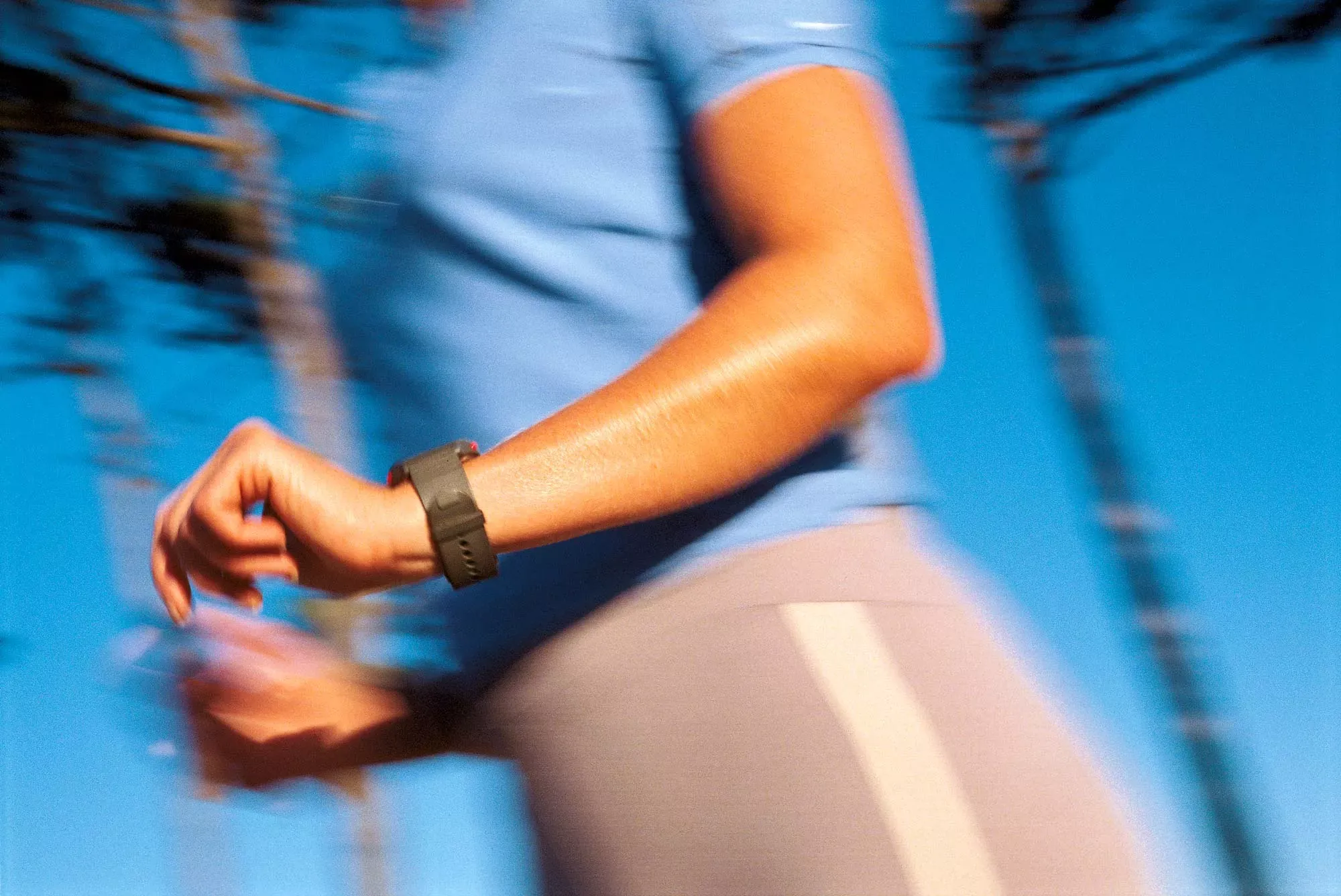 Frau schaut beim Joggen auf eine Smartwatch am Handgelenk. Frau schaut beim Joggen auf eine Smartwatch am Handgelenk.