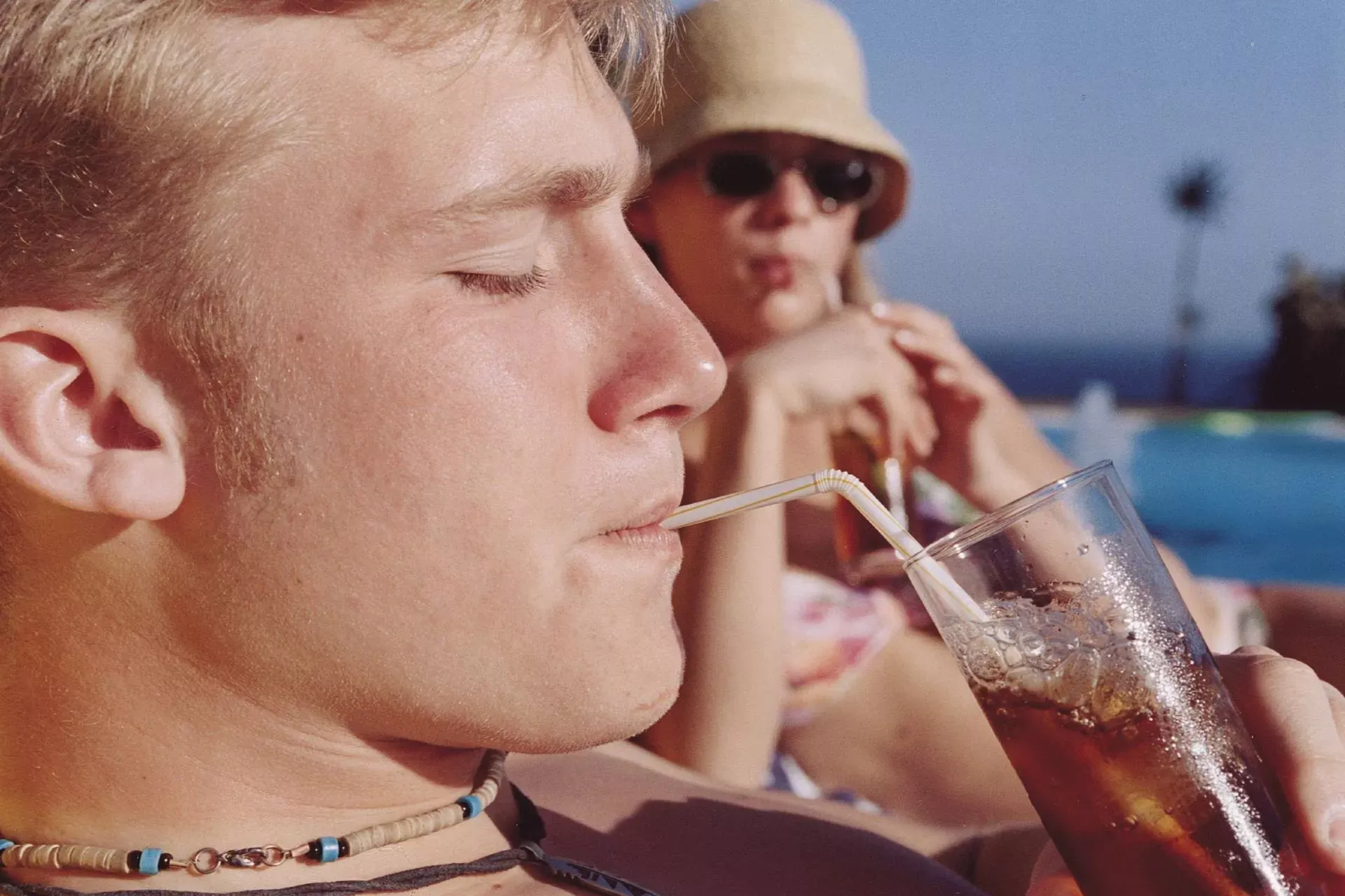Junger Mann trinkt Cocktail am Pool in der Sonne. Junger Mann trinkt Cocktail am Pool in der Sonne.