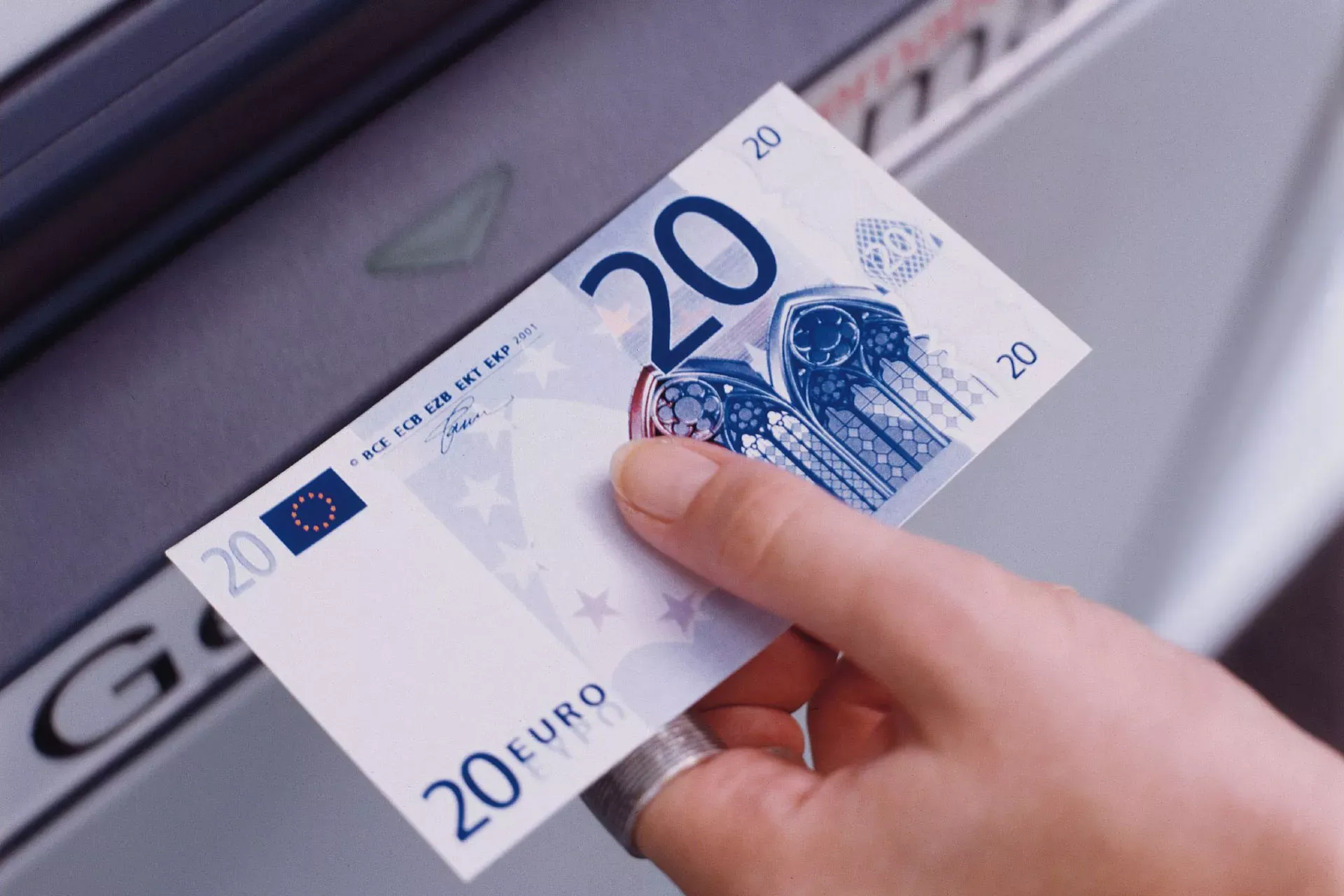 Hand zieht 20-Euro-Geldschein aus einem Geldautomaten. Hand zieht 20-Euro-Geldschein aus einem Geldautomaten.